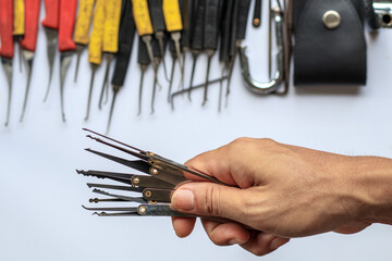 Many key picks in locksmith's hand are tools that require skill and practice to work in picking or...