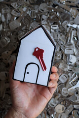 A white mockup house is placed on a blurred background of many keys to illustrate the security...