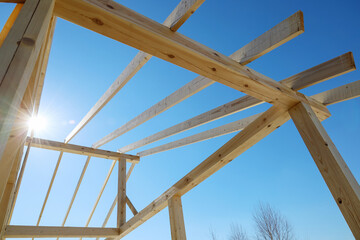 Obraz premium Supporting wooden structure for roof rafters, repeating beams on background of sky