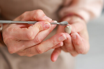 A woman makes a figure out of white clay