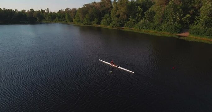 Sports canoe driven by team men women sailing along calm river with sun.