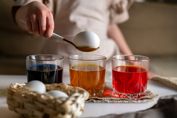 girl at home in the kitchen dyes eggs for Easter