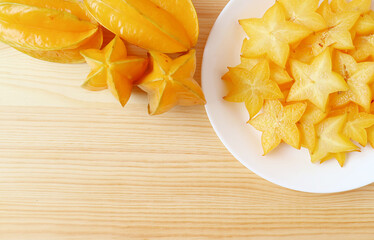 Heap of Fresh Ripe Starfruit with a Plate of Mouthwatering Juicy Slices on Wooden Background