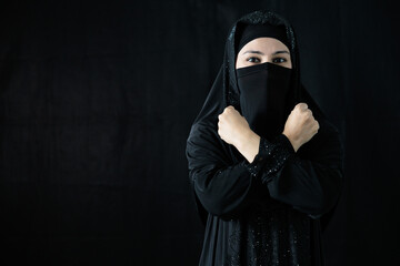 muslim woman in hijab showing fist punching gesture for against violence and human rights on black background