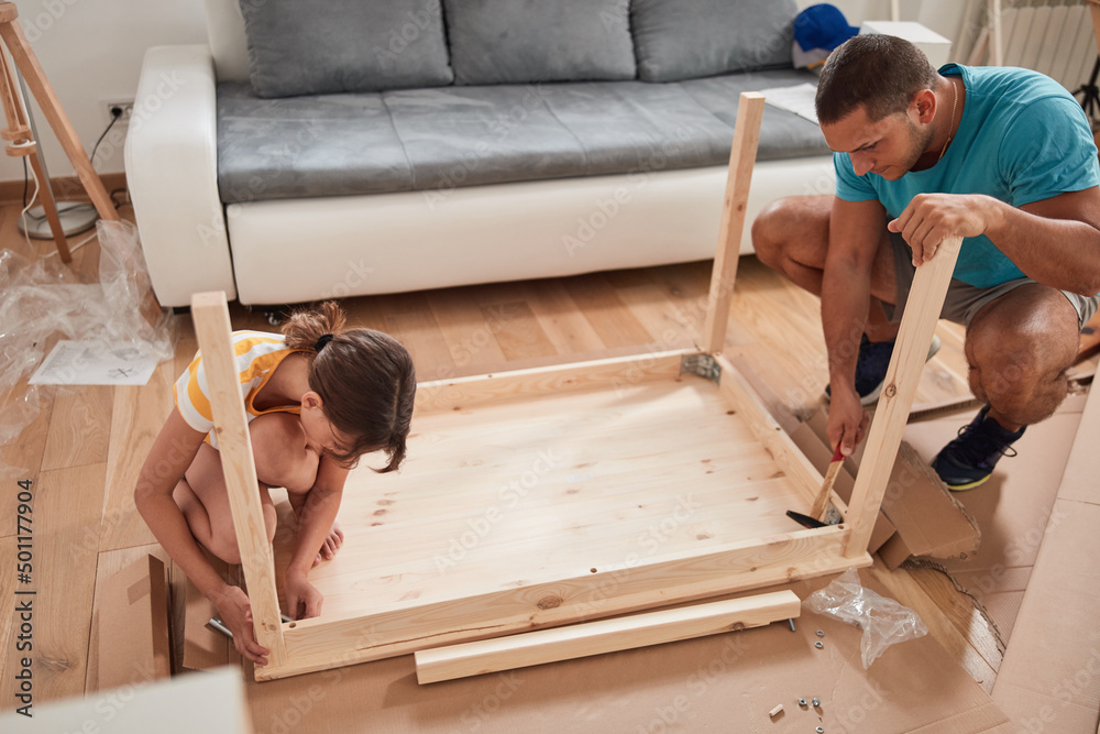 Wall mural father and daughter assembling new furniture - moving in into a new home.