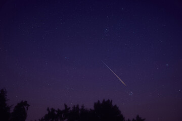 Stars, meteor trail on evening sky.