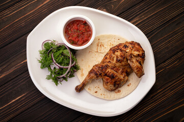 Grilled chicken half with sauce and herbs