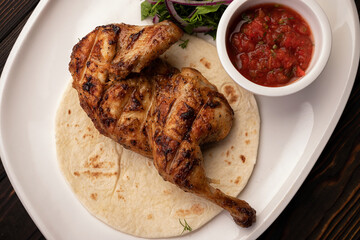 Grilled chicken half with sauce and herbs