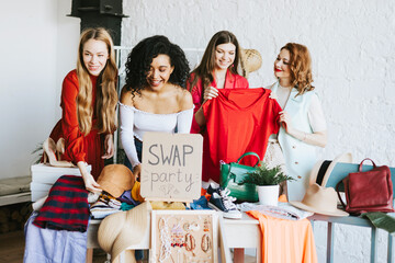 four young woman female caucasian and african students at swap party try on clothes, bags, shoes...