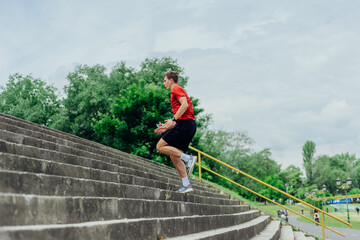 Fit male athlete performing stairs workout, running up climbing stairs performing outdoor track cardio..