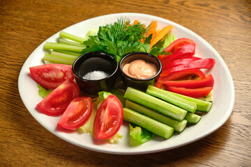 Fresh vegetables (cucumbers, tomatoes, dill, shallots) on a white plate