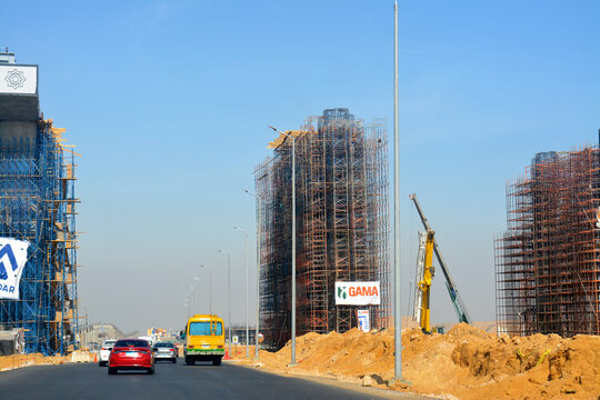 Cairo, Egypt, April 24 2022: A new traffic bridge for cars and vehicles under construction with the bridge concrete columns in a raw surrounded with steel and wood scaffolds and cranes at the site