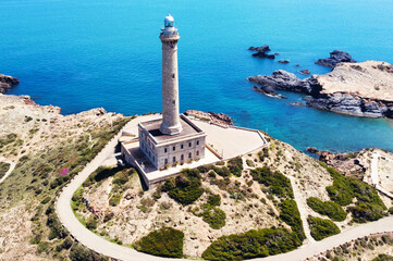 Bird's eye view of a beautiful lighthouse standing on the rocky coast of Spain near the sea.