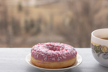 Coffee break and view from the window, city view. A Donut, a cup of coffee or tea, city view, blurred background.  Piece, quiet and a cup of coffee. Copy space, mock up