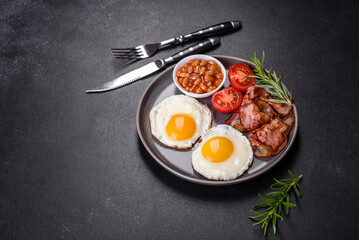 A delicious nutritious healthy breakfast with fried eggs, bacon, beans, a glass of juice, oat cookies, milk and jam