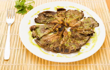 Typical Spanish food, grilled mushrooms with garlic. Close up view of food on a white plate.