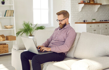 Serious young Caucasian businessman work online on laptop at home office. Middle-aged male freelancer busy with computer job consult client or customer on web. Lockdown, employment concept.