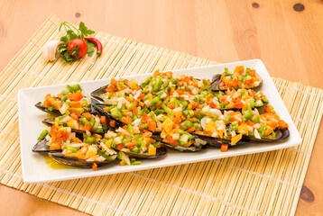 Typical Spanish food, mussels with vinaigrette. Close up view of food on a white plate.