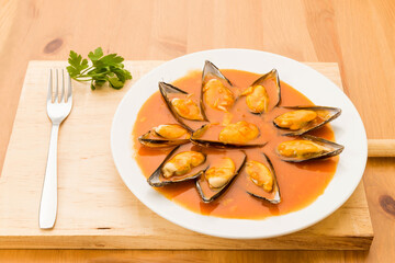 Typical Spanish food, mussels in sauce, Tiberius mussels. Close up view of food on a white plate.