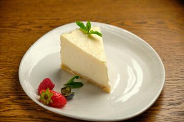 A piece of cheesecake, a classic New York-style cheesecake on a wooden table