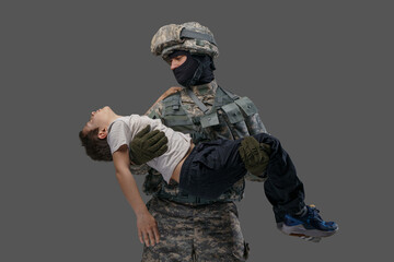 Shot of serviceman dressed in camouflage uniform rescuing little injured boy.