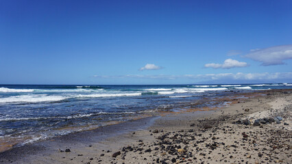 Tropical coastline on a sunny day in Las Americas, Tenerife, Canary Islands, Spain, natural beach, blue sky and waves 
