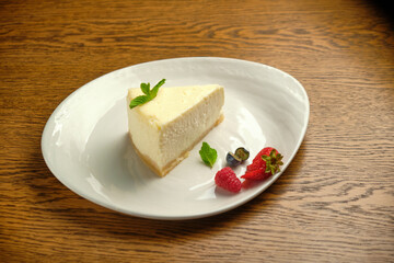 A piece of cheesecake, a classic New York-style cheesecake on a wooden table