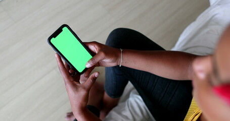 Black woman hands holding cellphone with green screen