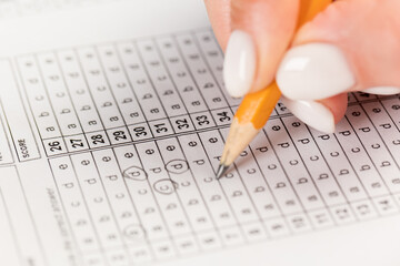 Students hands to take exams, writing an exam room with a pencil holding on an optical form of a standardized test with answers 