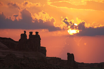 The famous "Wisemen" rock formation standing against a sunset sky at Arches National Park in Utah