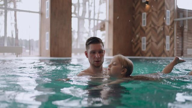 funny little girl is resting in pool, swimming with her dad and laughing, happy family vacation