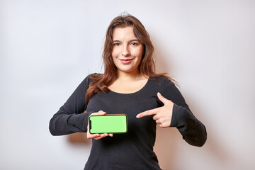 Naklejka premium Pretty girl holding a smartphone with a green display.