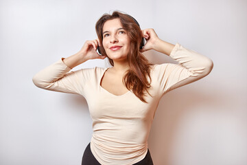 Beautiful girl with pleasure and a smile listens to music on headphones.