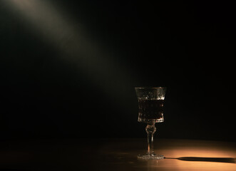 a lonely glass stands in a beam of light