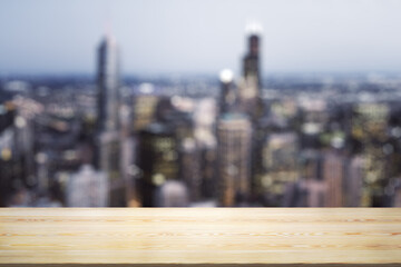 Empty wooden table top with beautiful blurry skyscrapers at evening on background, mock up