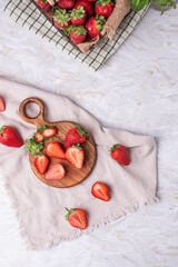 Erdbeeren im Drahtkorb auf einem Tisch mit Holzbrett und geschnittenen Erdbeeren und frische Minze,...