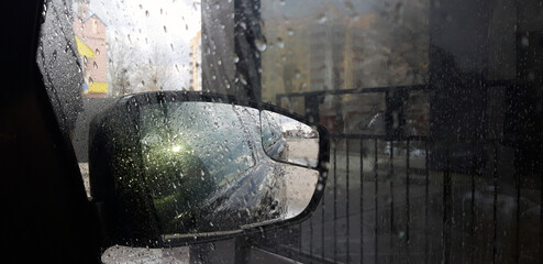 Car rearview mirror. Rain outside the window. Car at the wash.