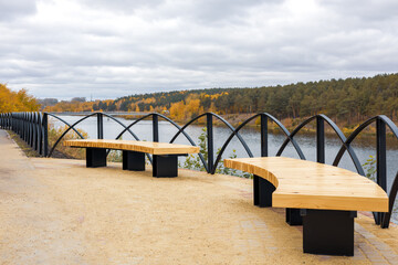 Fototapeta premium benches in the park in autumn time, background autumn forest and cloudy sky