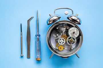 Fototapeta premium Watchmaker tools near watch mechanism of alarm clock