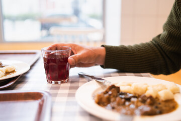 Man holding a glass of juice and eating traditional polish Gulasz at the restaurant