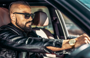 Stylish elegant man in sunglasses driving luxury car