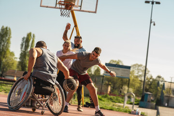 A physically challenged man in a wheelchair fearlessly engages in a spirited game of basketball with his supportive friends, breaking barriers and proving that passion and teamwork know no bounds.		 - 501199384