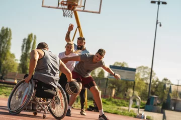 Fotobehang A physically challenged man in a wheelchair fearlessly engages in a spirited game of basketball with his supportive friends, breaking barriers and proving that passion and teamwork know no bounds.   © BalanceFormCreative