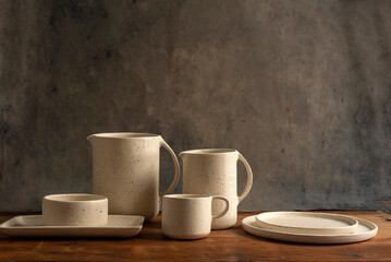 Artisan style cups and plates on wooden table and window light still life with homemade bread on the plates.