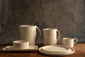 Artisan style cups and plates on wooden table and window light still life with homemade bread on the plates.