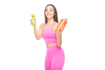 A beautiful, athletic, slim, smiling and cheerful woman in a pink tracksuit holds a dumbbell and a shaker with water. Lifestyle concept with sports and gym. Isolated on white background.