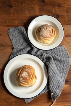 Artisan style cups and plates on wooden table and window light still life with homemade bread on the plates.