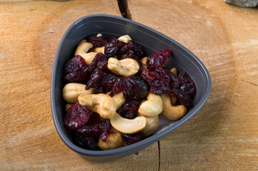 A mixture of nuts and dry berries. Variety of nuts and mixed berries. Snack in a plastic bowl. Plate on a wooden background.