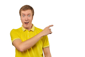 Surprised guy with funny face in bright yellow T-shirt pointing finger to right, white background