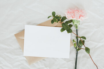 craft envelope, white sheet of paper, one pink carnation and green leaves, space for your text